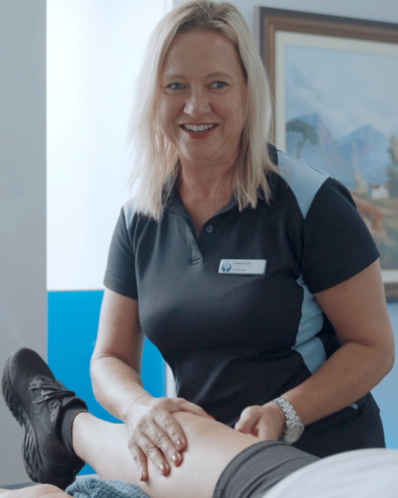 Assist Allied Health physiotherapist smiling, showcasing a strong connection and trust while working on a client's legs.